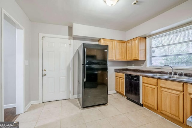 kitchen featuring dark countertops, black appliances, light tile patterned floors, and a sink