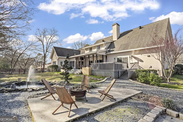 back of house featuring a fire pit, a patio, a chimney, a wooden deck, and stucco siding