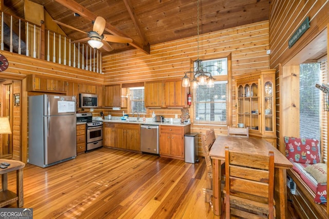 kitchen featuring a sink, light countertops, appliances with stainless steel finishes, brown cabinets, and pendant lighting