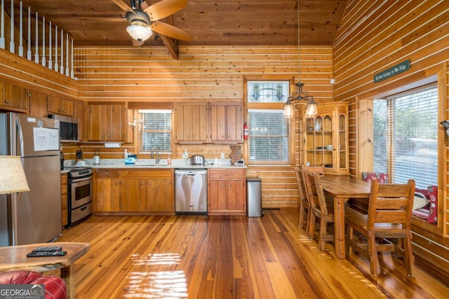 kitchen with stainless steel appliances, wood ceiling, brown cabinetry, and light wood finished floors