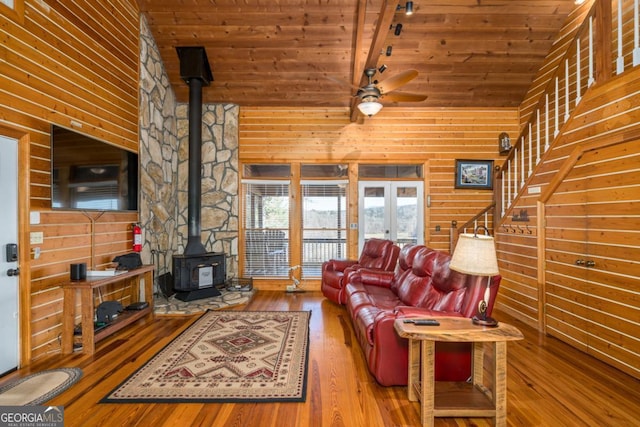 living room with ceiling fan, wooden ceiling, hardwood / wood-style flooring, wooden walls, and a wood stove