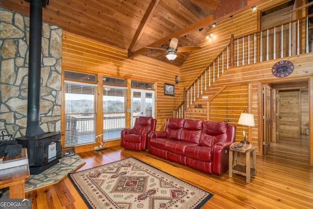 living room with hardwood / wood-style flooring, wood ceiling, stairs, beamed ceiling, and a wood stove