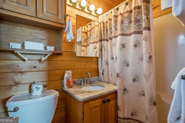 bathroom with vanity, toilet, and wooden walls