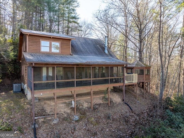 rear view of house with central AC unit and a sunroom