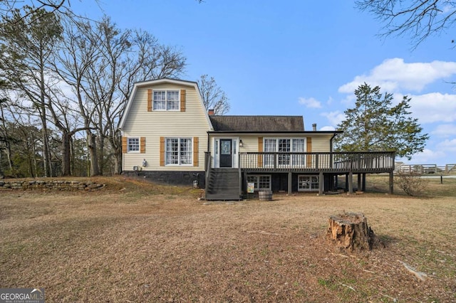 rear view of property with a chimney, a lawn, a deck, and a gambrel roof