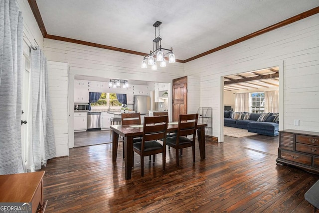 dining area with dark wood-style floors, ornamental molding, wooden walls, and an inviting chandelier