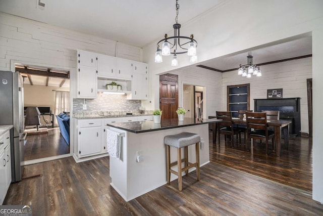 kitchen featuring a notable chandelier, hanging light fixtures, freestanding refrigerator, white cabinetry, and a kitchen island