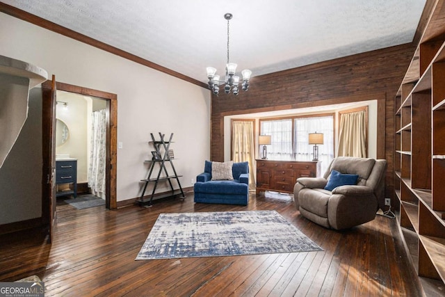 sitting room featuring dark wood-style floors, ornamental molding, baseboards, and an inviting chandelier