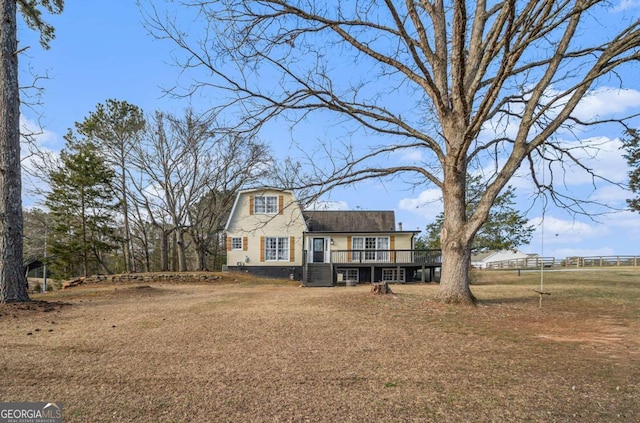 rear view of house with a yard, a deck, and a gambrel roof