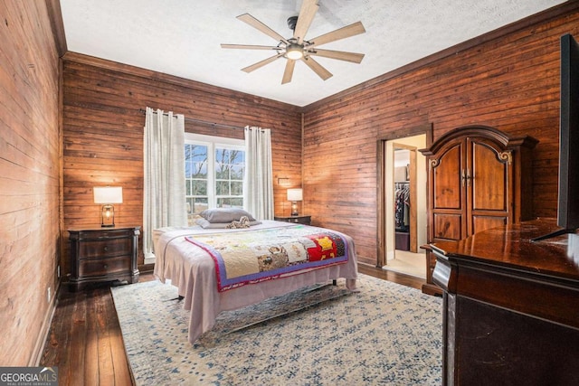 bedroom featuring wooden walls, dark wood-style flooring, ceiling fan, and a textured ceiling