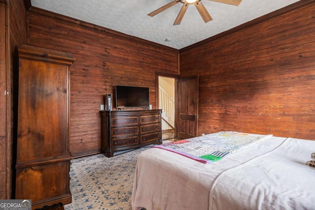 bedroom featuring wooden walls, light carpet, ceiling fan, and a textured ceiling