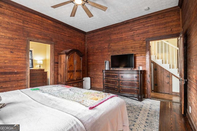 bedroom featuring a ceiling fan, wooden walls, and hardwood / wood-style flooring