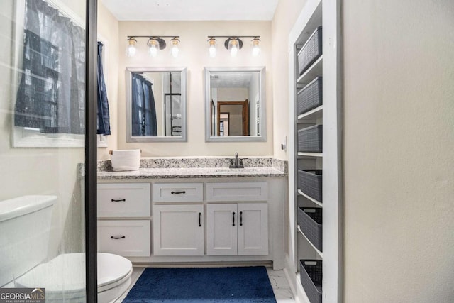 bathroom with marble finish floor, vanity, and toilet