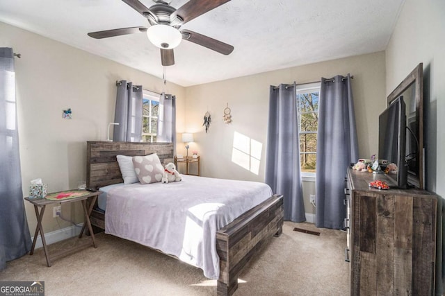 bedroom featuring light carpet, a ceiling fan, visible vents, and baseboards