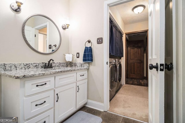 bathroom with washer and dryer, vanity, baseboards, and a textured ceiling