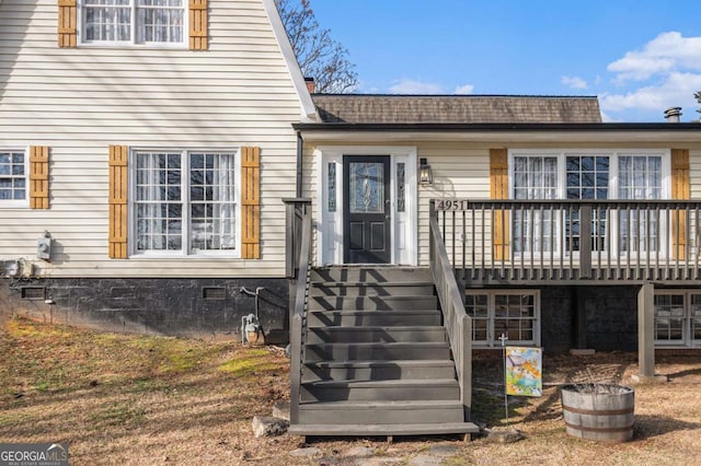 exterior space with roof with shingles and a wooden deck