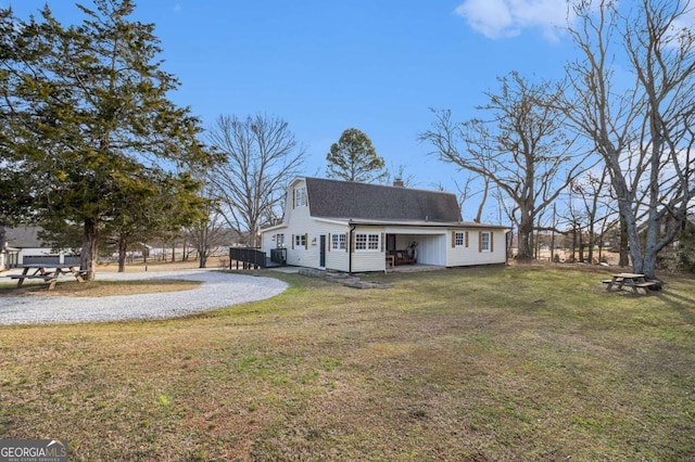 rear view of house featuring roof with shingles, a lawn, and a chimney