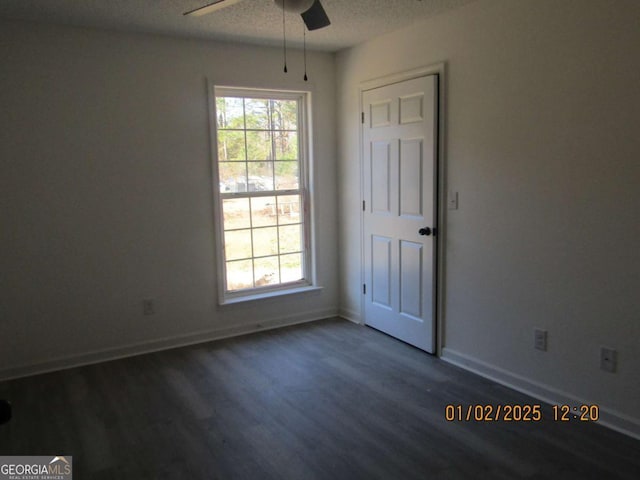 spare room featuring dark wood-type flooring, a textured ceiling, baseboards, and a ceiling fan