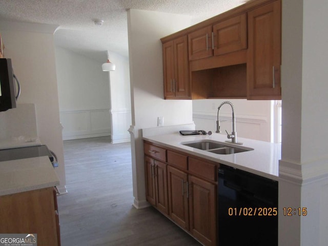 kitchen featuring black dishwasher, light countertops, stainless steel microwave, and a sink