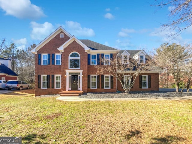 colonial home featuring brick siding and a front lawn