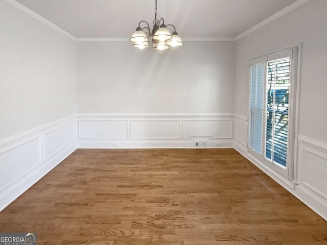 unfurnished dining area featuring crown molding, a chandelier, and wood finished floors