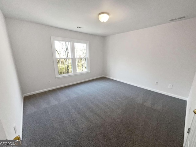 spare room featuring visible vents, dark carpet, and baseboards