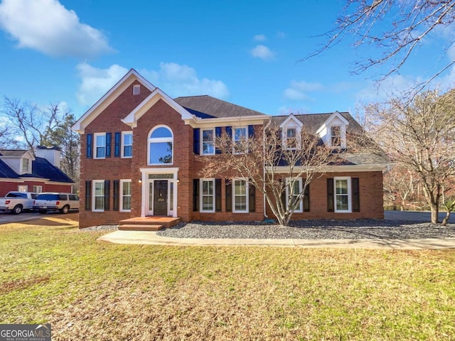 colonial inspired home featuring a front lawn and brick siding