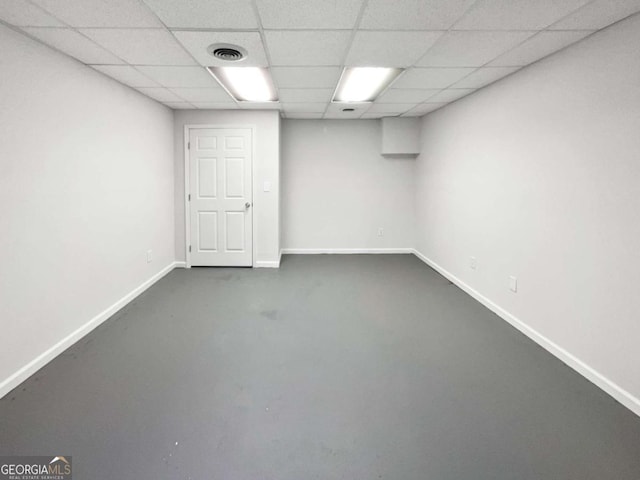 finished basement featuring visible vents, a drop ceiling, and baseboards