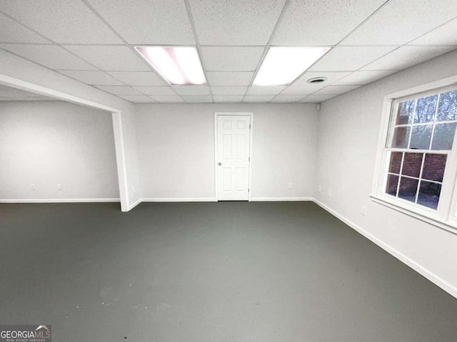 below grade area featuring a paneled ceiling and baseboards