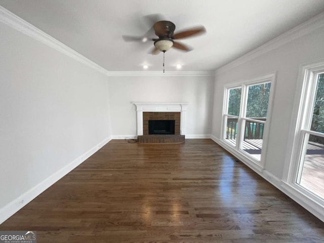 unfurnished living room with dark wood-style floors, a fireplace, ornamental molding, and baseboards