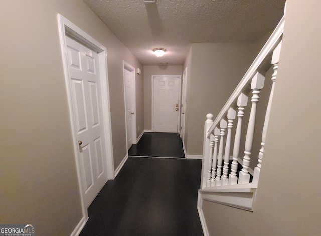 hall with dark wood-style floors, baseboards, stairway, and a textured ceiling