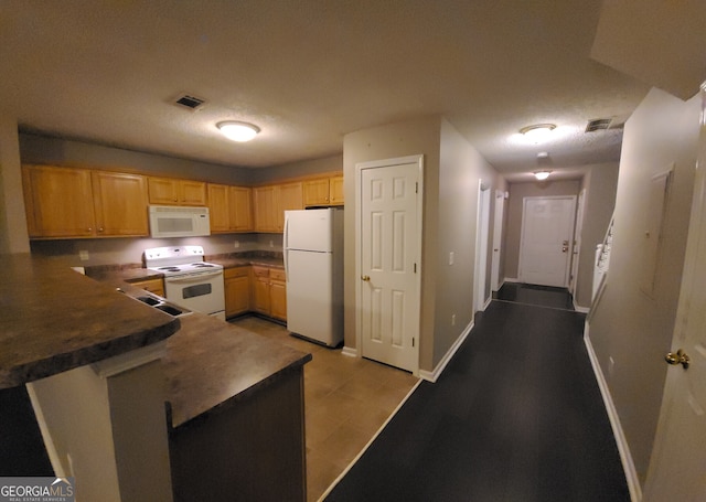 kitchen with dark countertops, white appliances, visible vents, and baseboards