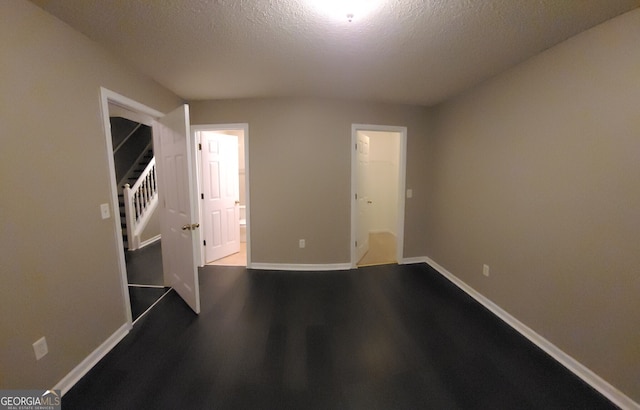 unfurnished room with stairs, a textured ceiling, baseboards, and wood finished floors