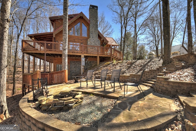 back of house with a patio, a chimney, an outdoor fire pit, a deck, and stairs