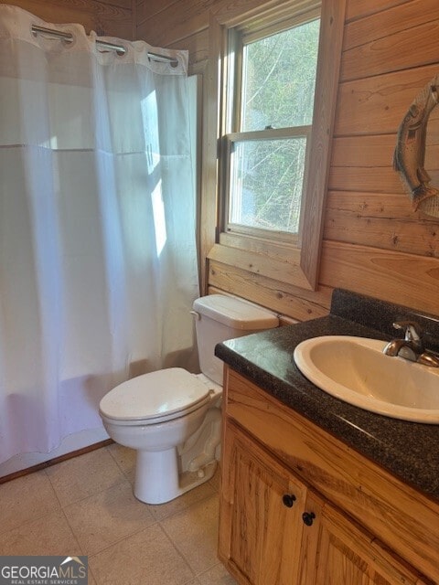 bathroom featuring curtained shower, toilet, wooden walls, vanity, and tile patterned floors