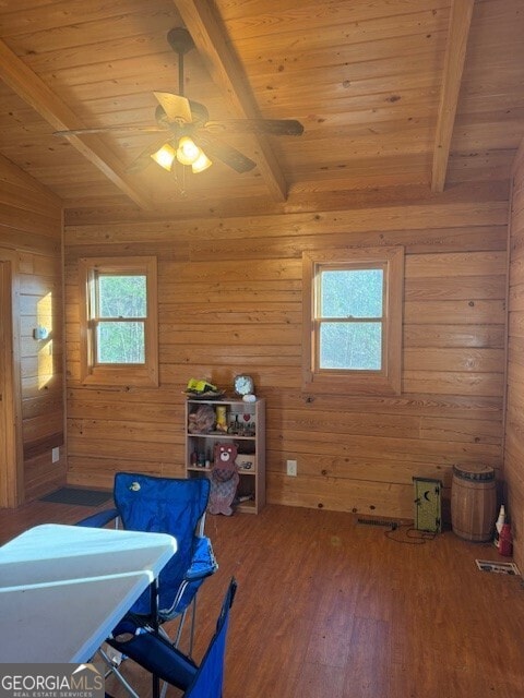 interior space featuring lofted ceiling with beams, a ceiling fan, wooden walls, wood finished floors, and wooden ceiling