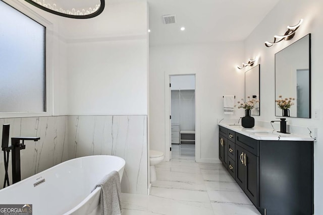 full bath with marble finish floor, visible vents, a freestanding bath, toilet, and a sink