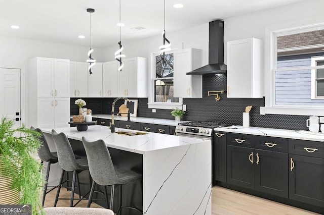 kitchen with wall chimney range hood, dark cabinets, white cabinets, and a sink