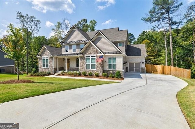 craftsman-style house featuring driveway, a garage, a standing seam roof, fence, and a front yard