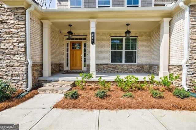 property entrance featuring stone siding, covered porch, and brick siding