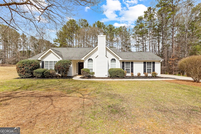 ranch-style home with a chimney, a front lawn, and roof with shingles