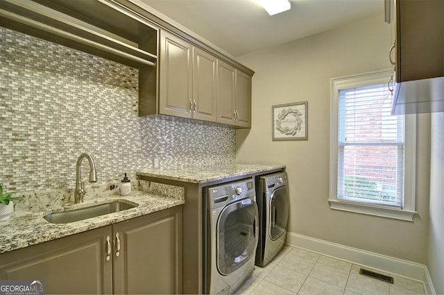 clothes washing area featuring light tile patterned floors, visible vents, washing machine and clothes dryer, cabinet space, and a sink