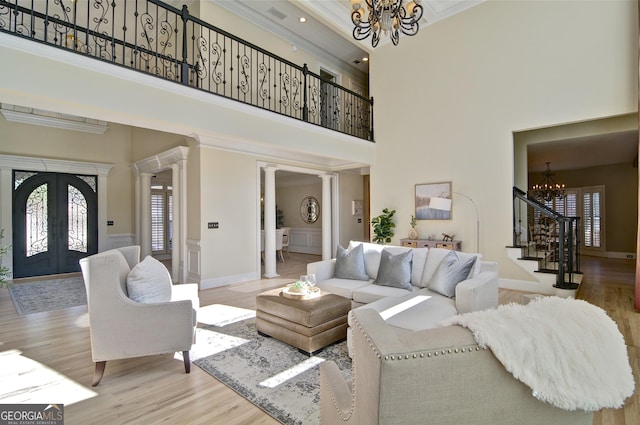 living room featuring stairway, wood finished floors, an inviting chandelier, french doors, and crown molding