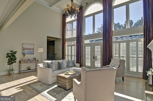 living room featuring a wealth of natural light, coffered ceiling, a high ceiling, and wood finished floors