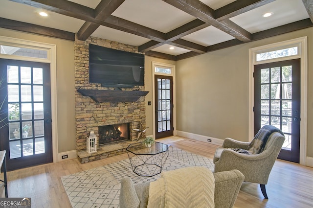 living area with wood finished floors, a healthy amount of sunlight, and coffered ceiling