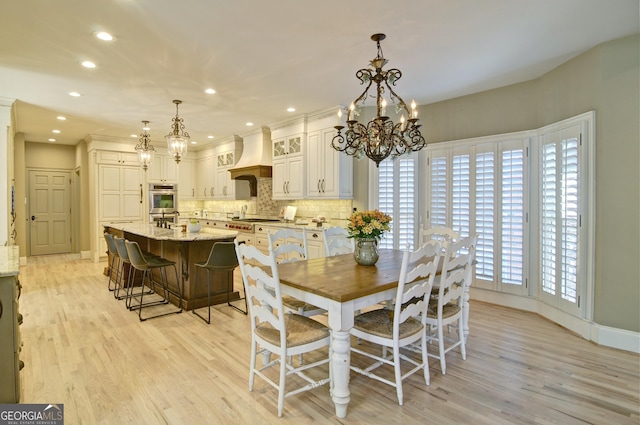 dining room featuring a notable chandelier, baseboards, and light wood finished floors