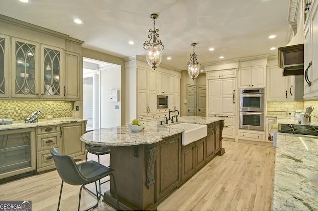 kitchen with a sink, light stone countertops, light wood-style floors, and stainless steel appliances