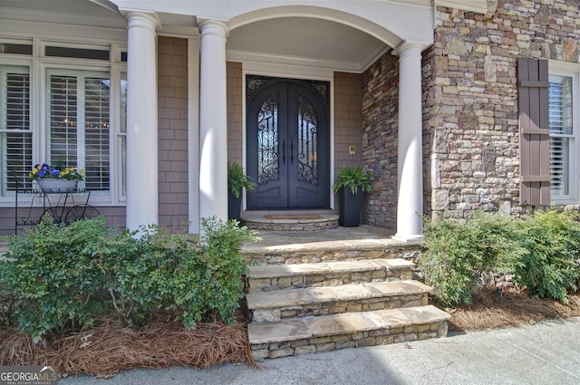 entrance to property with a porch and stone siding