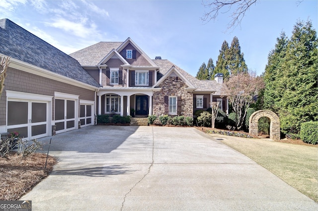 view of front of property with driveway, an attached garage, a chimney, a front lawn, and stone siding