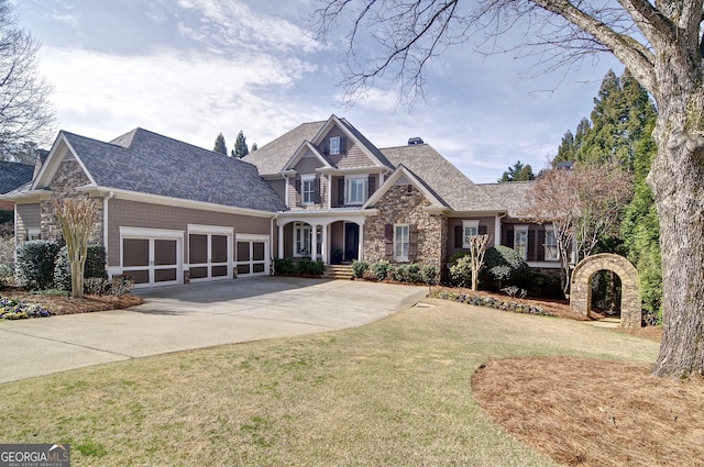 view of front of home featuring concrete driveway, an attached garage, a front yard, and stone siding